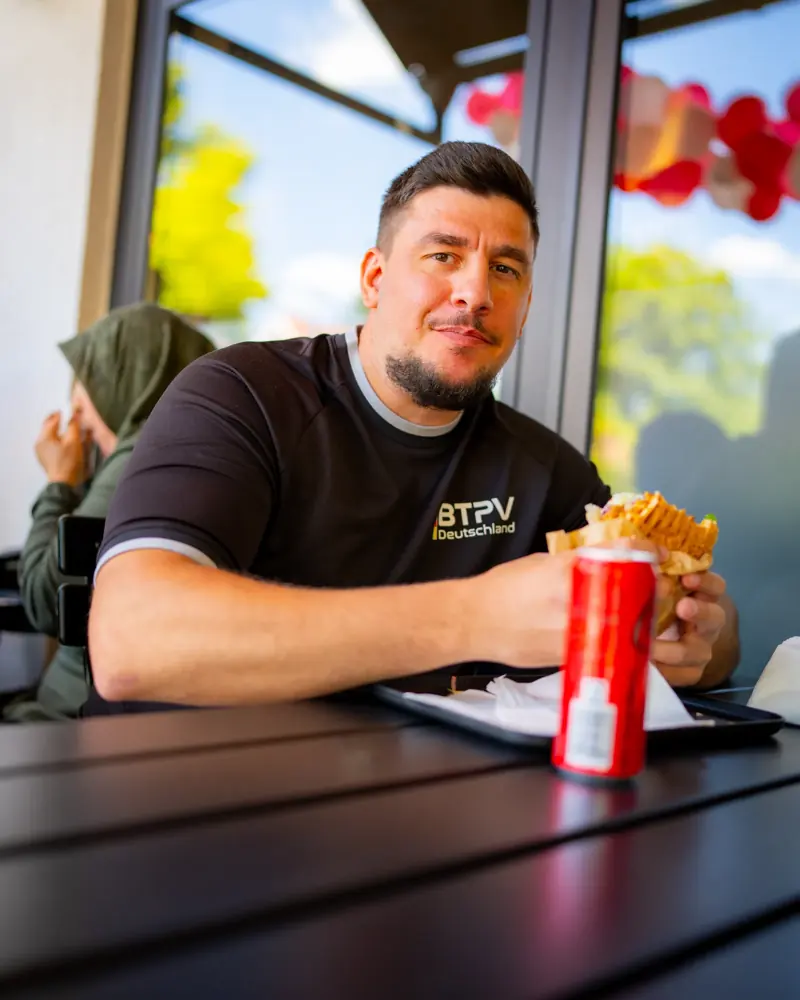 Entspannter Gast mit Getränk und Döner am Tisch bei Amca's Kebab